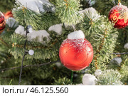 Green plastic Christmas tree outside with snow and red glass balls. Christmas decorations. Стоковое фото, фотограф Татьяна Куклина / Фотобанк Лори