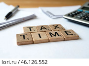 Tax Time text on wooden cube with calculator, pen and notebook on wood background. Стоковое AI-изображение, AI-художник Васильева Юлия / Фотобанк Лори