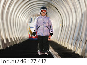 A girl on skis stands on a carpet ski lift in a glass tunnel. Стоковое фото, фотограф Irina Kuchugurina/Gaudy / Фотобанк Лори