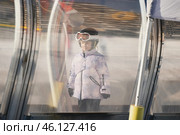 A girl on skis stands on a carpet ski lift in a glass tunnel. Стоковое фото, фотограф Irina Kuchugurina/Gaudy / Фотобанк Лори