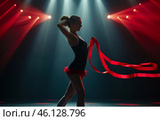 Dancer performing with red ribbons under dramatic stage lights in a vibrant studio setting during an evening performance. Стоковое AI-изображение, AI-художник Sergey Grishin / Фотобанк Лори