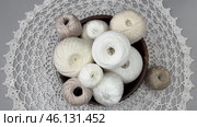 Time lapse video of white balls of cotton yarn for hand crochet in placed by female hand in wooden plate on handmade lace napkin on light table. Set of wooden hooks nearby. Flat lay, close-up. Стоковое видео, видеограф Виктория Катьянова / Фотобанк Лори
