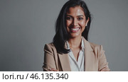 Confident indian businesswoman smiling with folded arms on gray background. Стоковое видео, видеограф Данил Руденко / Фотобанк Лори