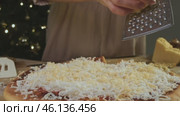 Housewife cooks pizza at home according to a traditional Italian recipe by grating cheese on a fine grater. Стоковое видео, видеограф Strunov David / Фотобанк Лори