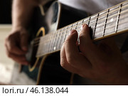 Playing the guitar. Strumming acoustic guitar. Musician plays music. Man fingers holding mediator. Man hand playing guitar neck in dark room. Unrecognizable person rehearsing, fretboard close-up. Стоковое фото, фотограф Марина Демидюк / Фотобанк Лори