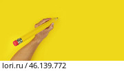 Yellow big pencil in left hand on bright yellow background with copy space. Стоковое фото, фотограф Kira_Yan / Фотобанк Лори