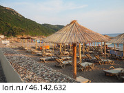 Canj, Montenegro: 07.20.2024 Sun loungers and straw umbrellas line the shore at Bar Beach, creating a serene atmosphere for relaxation by the calm waters on a sunny day. Adriatic Mediterranean Sea. Редакционное фото, фотограф Юлия Петровская / Фотобанк Лори