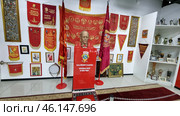 An exhibition of the Soviet era in the USSR Museum, dedicated to the ideology, awards and symbols of the Soviet Union. The central place is occupied by a bust of V.I. Lenin on a red pedestal with the inscription:"V.I. LENIN (ULYANOV) FOUNDED THE USSR IN 1922."Red banners, pennants, awards and portraits of Soviet leaders are placed around. On the walls you can see Soviet slogans, paintings and memorable relics.Red banners with the symbols of the USSR, including the coat of arms and slogans.The bust of Lenin is the central exhibit, surrounded by Soviet paraphernalia.An exhibition of orders and badges, displaying the history of USSR awards.Posters and portraits of leaders (Lenin, Soviet propaganda).Historical relics in glass cases, including dishes, souvenirs and awards.Tapestries and carpets with symbols of the USSR.Retro atmosphere, recreating the spirit of the Soviet era. (2023 год). Редакционное фото, фотограф Анна Кривицкая / Фотобанк Лори