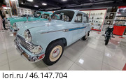 Classic Soviet car "Moskvich-407", located in the USSR museum. This car was produced by the Moscow Plant of Small Cars (AZLK) from 1958 to 1963. The car is painted light blue with characteristic chrome details, such as the radiator grille, bumpers and mirrors.The "Moskvich-407" car is a classic of the Soviet automobile industry.Light blue body color, shiny chrome details.Retro hubcaps on the wheels, branded "Moskvich" emblems.Nearby is another Soviet car, probably "Pobeda" GAZ-M20.Display cases with antiques - old watches, household items of the USSR.A Soviet-made motorcycle on the right side of the frame.An exposition dedicated to the USSR, with items of the era. (2023 год). Редакционное фото, фотограф Анна Кривицкая / Фотобанк Лори
