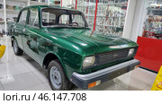 Retro car "AZLK Moskvich-2140", painted in a rich green color. This Soviet-made car was produced at the Moscow Automobile Plant (AZLK) in the 1970-1980s. The car is in the USSR Museum, surrounded by display cases with porcelain figurines, crystal and other items of Soviet life.Classic Soviet car with a characteristic design.Green body paint, shiny chrome bumper.The signature "AZLK" emblem and the "Moskvich-2140" model on the front.Museum setting, glass display cases with items from the Soviet era.Caution, wet floor! - warning sign on the floor.Retro-style museum interior with red design elements. (2023 год). Редакционное фото, фотограф Анна Кривицкая / Фотобанк Лори