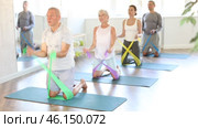 Elderly man performs exercises with elastic rubber band during Pilates strength training, kneeling. Стоковое видео, видеограф Яков Филимонов / Фотобанк Лори