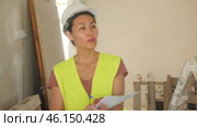 Portrait of a focused woman builder in a hardhat and vest, attentivelly checking the construction panels. Стоковое видео, видеограф Яков Филимонов / Фотобанк Лори