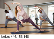 Woman doing Utthita Parsvakonasana during group yoga workout. Стоковое фото, фотограф Яков Филимонов / Фотобанк Лори