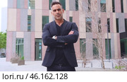 Confident businessman standing with arms crossed in urban setting.Vertical. Стоковое видео, видеограф Raquel Corcoles Mendez / Фотобанк Лори