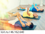 Mom, grandmother and teen grandson do preparatory stretching, lying on back and benting leg at knee. Стоковое фото, фотограф Яков Филимонов / Фотобанк Лори