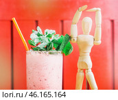 Wooden figure celebrates with refreshing minty drink in a vibrant setting. Стоковое фото, фотограф Сергей Толмачёв / Фотобанк Лори