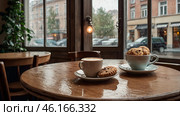 A white cup of hot coffee and biscuits on a table in a modern cozy cafe by the window. It's raining outside. The concept of comfort and warmth. Стоковое AI-изображение, AI-художник Photojuli / Фотобанк Лори