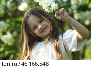 Close up little girl in a white dress touches the bloom white lilac flowers while walking in park and smells the scent of spring flowers. Spring time and awakening. Children and nature. Стоковое фото, фотограф Ирина Михайличенко / Фотобанк Лори