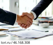 Деловое рукопожатие на фоне документов, лежащих на столе. Стоковое AI-изображение, AI-художник Руслан Лесков / Фотобанк Лори