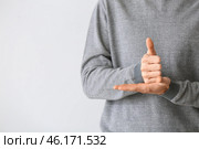 Young deaf mute man using sign language on light background. Стоковое фото, фотограф Pixel_shot / Фотобанк Лори