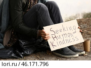 Poor homeless man holding cardboard with text SEEKING HUMAN KINDNESS outdoors. Стоковое фото, фотограф Pixel_shot / Фотобанк Лори