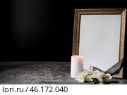Blank funeral frame, candle and flowers on table against black background. Стоковое фото, фотограф Pixel_shot / Фотобанк Лори