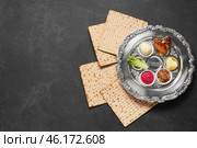 Passover Seder plate with traditional food and matza on dark background. Стоковое фото, фотограф Pixel_shot / Фотобанк Лори