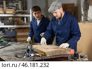 Carpenter measures the length of board with tape measure. Foreman prompts him. Стоковое фото, фотограф Яков Филимонов / Фотобанк Лори