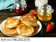 Blini served with strawberry jam, honey, sour cream and fresh berries. Dark wooden table, high resolution. Стоковое фото, фотограф Юлия Фатеева / Фотобанк Лори