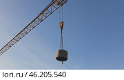The tower crane slowly and confidently lifts the massive concrete ring. The ring is moved to the storage warehouse, the cargo hangs on strong cables while the crane carefully moves. Стоковое видео, видеограф Скрипачев Антон / Фотобанк Лори