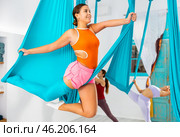 Young women making antigravity yoga exercises with group of people. Стоковое фото, фотограф Яков Филимонов / Фотобанк Лори