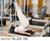 Guy performing reverse crunches with legs raises on Pilates reformer. Стоковое фото, фотограф Яков Филимонов / Фотобанк Лори