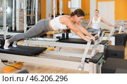 Girl in different poses performs static and dynamic exercises on reformer. Стоковое фото, фотограф Яков Филимонов / Фотобанк Лори