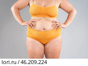 Tummy tuck, flabby skin on a fat belly, abdomen with obesity and cellulite, saggy stomach, plastic surgery concept on gray background. Стоковое фото, фотограф Станислав Тарко / Фотобанк Лори