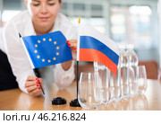 Unrecognizable girl sets midget flags of Russia and European Union before international negotiations. Стоковое фото, фотограф Яков Филимонов / Фотобанк Лори