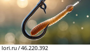 Close-up of a fishing hook with a bait worm hanging in the sunlight at a serene lakeside setting. Стоковое AI-изображение, AI-художник Сергей Толмачёв / Фотобанк Лори