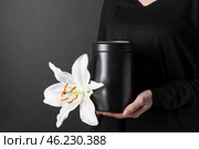 Woman with mortuary urn and lily flower on dark background, closeup. Стоковое фото, фотограф Pixel_shot / Фотобанк Лори