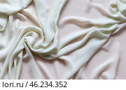 Top view of twisted white silk fabric. Textile abstract background. Material for sewing and cutting. Sewing and needlework as a hobby. Flat lay, close-up, copy space, mock up. Стоковое фото, фотограф Виктория Катьянова / Фотобанк Лори