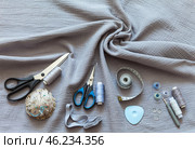 Top view of twisted cotton muslin fabric. Sewing accessories for sew and cutting on fabric - threads, needles, buttons, scissors, tailor chalk, pincushion. Sewing as a hobby. Flat lay, closeup, copy space. Стоковое фото, фотограф Виктория Катьянова / Фотобанк Лори