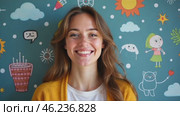 Woman is smiling in front of a wall with a lot of drawings on it. Стоковое AI-видео, аниматор Sergey Grishin / Фотобанк Лори