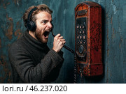 Мужчина в свитере громко кричит в телефон, демонстрируя эмоции и злость по поводу телефонного мошенничества. Стоковое AI-изображение, AI-художник Сергей Никифоров-Гордеев / Фотобанк Лори
