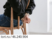Female hostage with tied hands sitting on chair in room. Стоковое фото, фотограф Pixel_shot / Фотобанк Лори