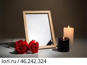 Photo frame with carnation flowers and candles on table against dark background. Стоковое фото, фотограф Pixel_shot / Фотобанк Лори