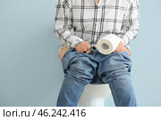 Elderly woman with paper sitting on toilet bowl against color background. Concept of hemorrhoids. Стоковое фото, фотограф Pixel_shot / Фотобанк Лори