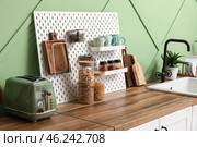 Pegboard with cookware and spices near green wall in kitchen. Стоковое фото, фотограф Pixel_shot / Фотобанк Лори
