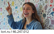 Woman is smiling and pointing at a wall with a lot of drawings on it. Стоковое AI-видео, аниматор Sergey Grishin / Фотобанк Лори
