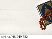 Koran and Muslim prayer beads on white wooden background. Стоковое фото, фотограф Pixel_shot / Фотобанк Лори