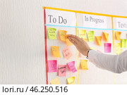 Man attaching sticky note to scrum task board in office. Стоковое фото, фотограф Pixel_shot / Фотобанк Лори