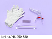 Medical gloves with gynecological speculum and pap smear test tools on lilac background. Стоковое фото, фотограф Pixel_shot / Фотобанк Лори