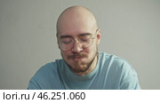 A bald man is enjoying a piece of fast food with great pleasure. He enjoys eating unhealthy food and has no manners. Portrait. Стоковое видео, видеограф Strunov David / Фотобанк Лори